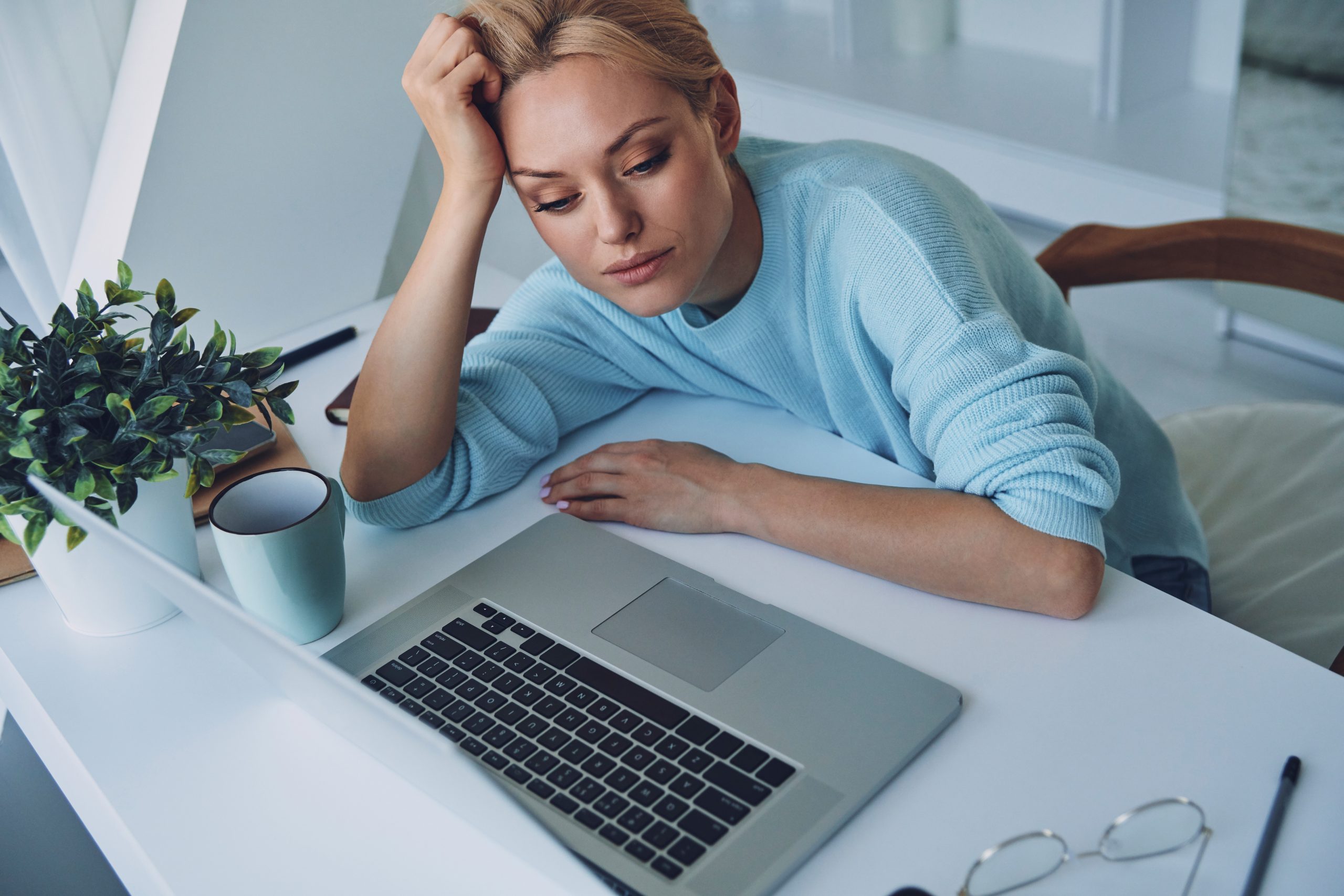 Top view of tired young woman using laptop while working in office